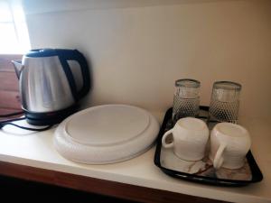 a counter with a coffee maker and a tray with plates and cups at Vijayaa Homes in Tiruvannāmalai