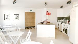 a white kitchen with white tables and white chairs at Hostal SA Roqueta Mahon in Mahón