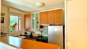 une cuisine avec des armoires en bois et un réfrigérateur en acier inoxydable dans l'établissement Appartement 4 personnes 10 min Disney, à Montévrain 10 autres photos