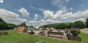 eine Terrasse mit Picknicktischen und Bänken in einem Park in der Unterkunft Ursula in Hope