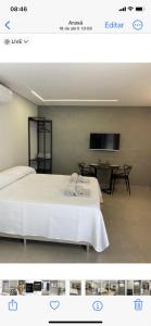 a bedroom with a white bed and a tv at Loft ARAXÁ in Araxá