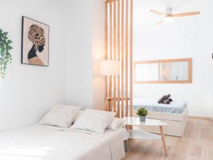 Un dormitorio blanco con una cama y una mesa. en Estudio Jacuzzi con Encanto en Triana, en Sevilla