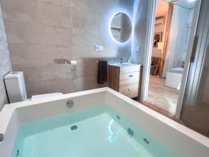 y baño con bañera grande y espejo. en Estudio Jacuzzi con Encanto en Triana, en Sevilla
