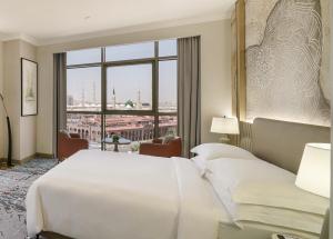 a hotel room with a bed and a large window at Rotana Al Manakha Madinah in Al Madinah