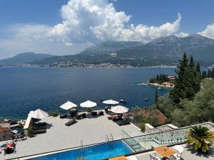 a swimming pool with a view of a lake and mountains at Agape Rose Hotel in Tivat