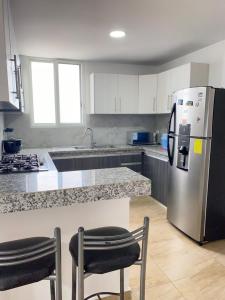 cocina con nevera de acero inoxidable y 2 sillas en Kattyapartament 1103vista al mar, en Salinas