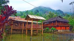 two wooden houses in a village with mountains in the background at A Páo Homestay in Bản Hon