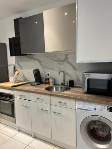 una cucina con lavello e lavatrice di Grand T2 climatisé avec jardin et spa a Narbonne