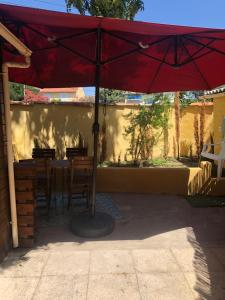 un ombrello rosso seduto sopra un tavolo di Grand T2 climatisé avec jardin et spa a Narbonne