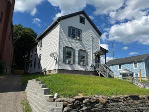 a white house on a hill with a stone wall at Home Plate Apt 2 All Star Baseball Rentals in Oneonta
