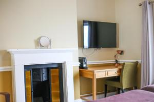 a room with a fireplace and a desk and a tv at The Wellington Hotel in Ventnor