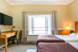 a hotel room with a bed and a desk and a window at The Wellington Hotel in Ventnor