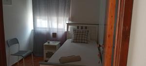 a small bedroom with a bed and a chair at quartos da praia in Peniche