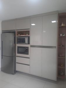 a kitchen with white cabinets and a refrigerator at Quarto em casa compartilhada in Petrolina