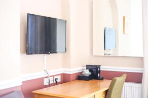a room with a desk with a television on the wall at The Wellington Hotel in Ventnor