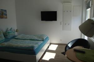 a bedroom with a bed and a chair and a television at Ferienquartier Trassenheide 1 in Trassenheide