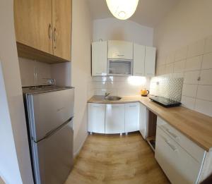 kuchnia z białymi szafkami, zlewem i lodówką w obiekcie Apartamenty Kolorowe Etna w Kołobrzegu