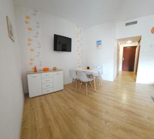 salon ze stołem, krzesłami i telewizorem w obiekcie Apartamenty Kolorowe Etna w Kołobrzegu
