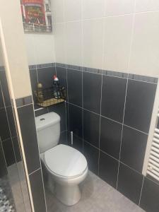 a bathroom with a white toilet and black tiles at Maison de charme st euphemie in Sainte-Euphémie