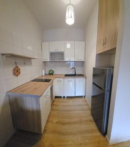 kuchnia z białymi szafkami i drewnianą podłogą w obiekcie Apartamenty Kolorowe Etna w Kołobrzegu