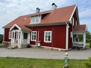 a little boy walking in front of a red house at Böllingetorps gamla skola i Småland in Sävsjö