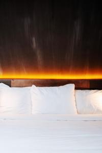 a bed with white pillows in front of a wall at City Center Lodge Utrecht in Utrecht
