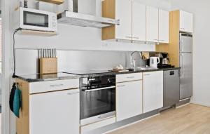 une cuisine avec des armoires blanches et des appareils en acier inoxydable dans l'établissement Gudhjem Søpark Lejl 35, à Gudhjem