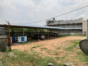a building with cars parked under a blue roof at Hotel MPS in Tiruppūr