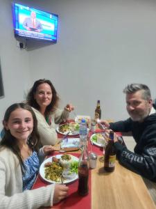 a group of people sitting at a table with plates of food at Meuly Family Lodge in Arusha