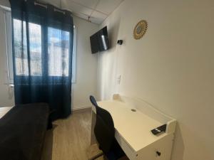 a room with a table and a tv on the wall at Hôtel du Colombier Rennes Centre Gare in Rennes