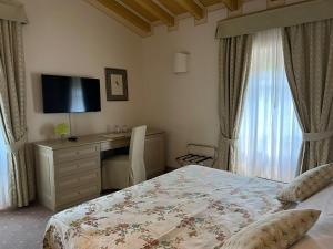 a bedroom with a bed and a desk with a television at Romantik Hotel Relais Mirabella Iseo in Iseo
