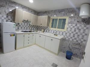 a kitchen with white cabinets and a stone wall at جودة الحياة in Al Kharj