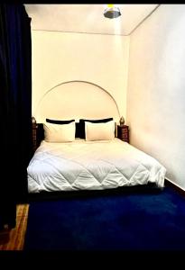 a bedroom with a white bed with a blue carpet at Dar Tadout in Aït Ourir