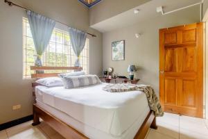 a bedroom with a large white bed and a wooden door at Idilio Escape in Ocho Rios