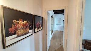 two framed pictures on a wall with a basket of fruit at Donna Maria Ludovica in Pescia Romana