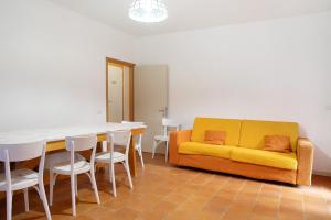 a living room with a yellow couch and a table and chairs at Casa Nel Bosco in Sacco