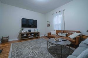 a living room with a couch and a table at Cozy 2BR-Walk to Tufts & Green Line, Near Boston! in Medford