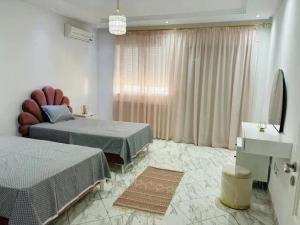 a bedroom with two beds and a television in it at Villa Piscine Hergla in Akouda