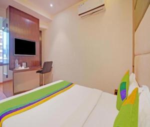 a bedroom with a bed and a desk and a tv at Glitz Hotels The Pacific - Nr Solitaire Corporate Park in Mumbai