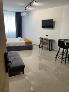 a living room with a bed and a table and a television at Thess Living Suites in Thessaloniki