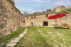 a red umbrella in the yard of a stone building at Cal Sastre in Biscarri