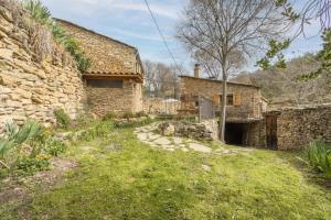 an old stone house with a yard next to a building at Cal Sastre in Biscarri