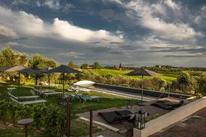 a patio with umbrellas and lounge chairs and a pool at Borgo Elissa Country Relais in Certaldo