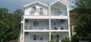 a white apartment building with a balcony and trees at Apartman Stefan in Tivat