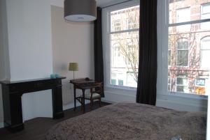 Schlafzimmer mit einem Bett, einem Schreibtisch und einem Fenster in der Unterkunft Bed & Breakfast Obrechtstraat in Den Haag