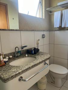 a bathroom with a sink and a toilet and a mirror at Apto Golden Dolphin in Caldas Novas