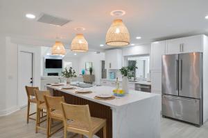 a kitchen with a large island with chairs and a refrigerator at Sea Glass Villa- Executive Pool Home on Golf Course in Sanibel