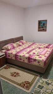 a bedroom with a bed with a pink and white comforter at Apartmani Stanić in Sutomore