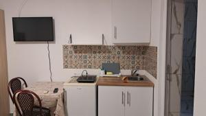 a kitchen with a table and a sink and a tv at Apartmani Stanić in Sutomore