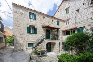 an old stone house with green shutters on a street at Kruna apartments est 2024 in Split